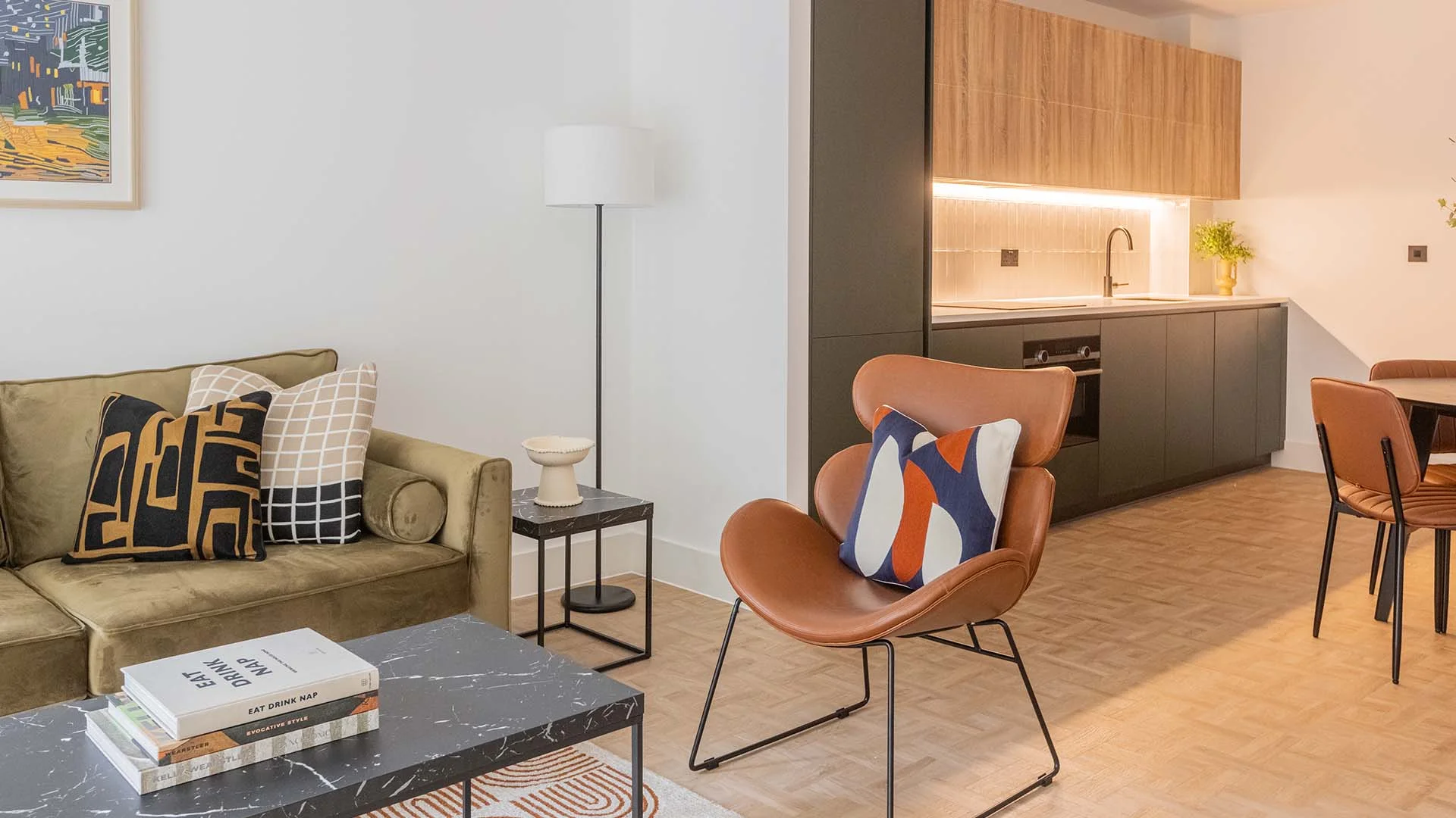 Modern living room with sofa, armchair, coffee table and contemporary artwork in Papillon Apartments Residence Two London