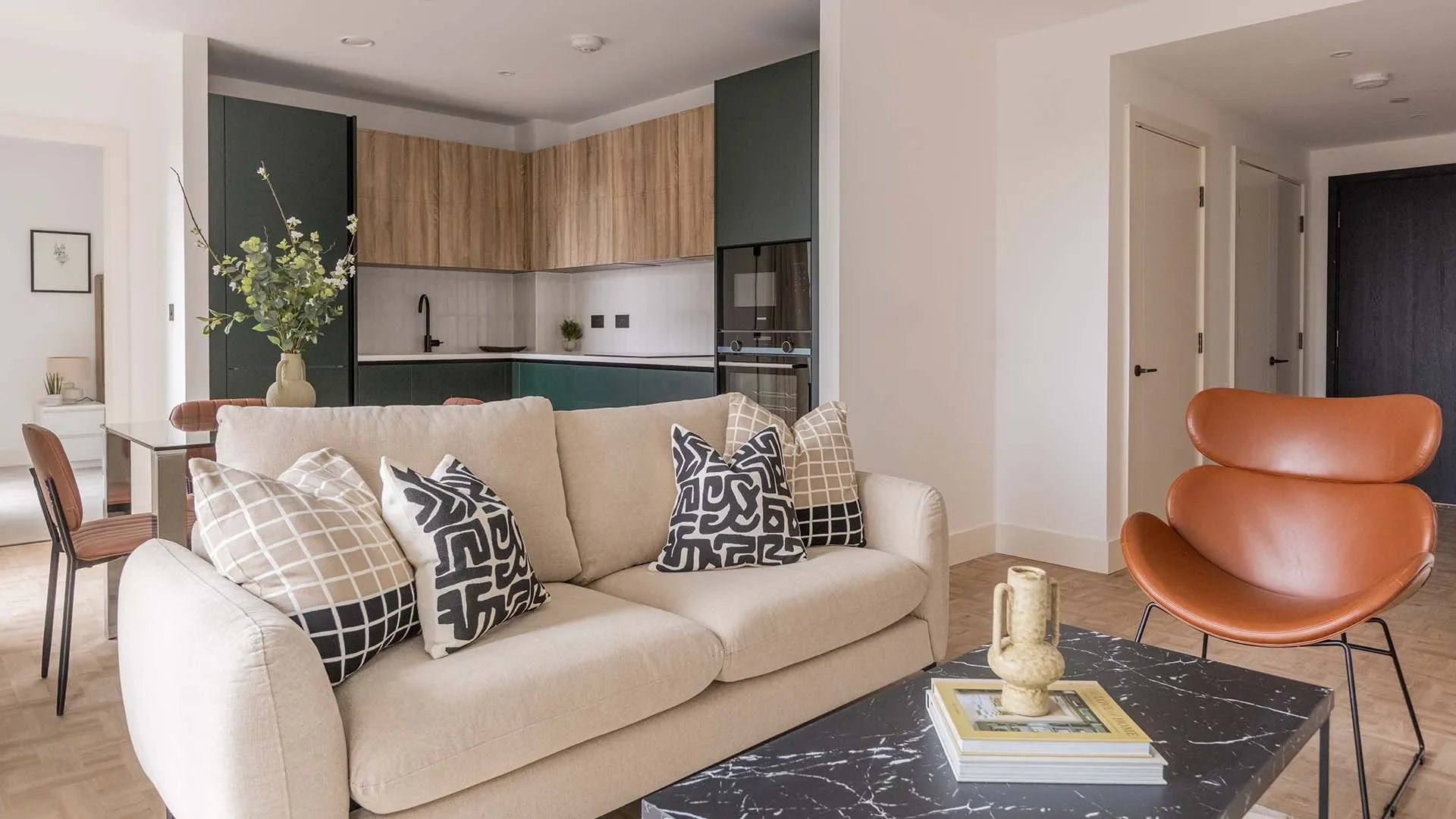 Modern furnished living room with beige sofa and open kitchen interior