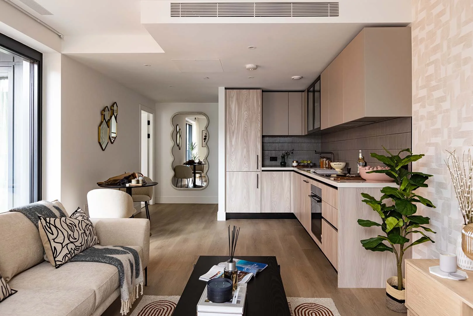 Modern open-plan apartment with living room sofa, dining area, and contemporary kitchen design