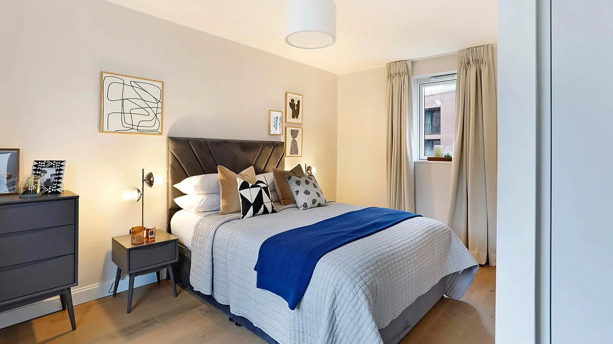 Modern build-to-rent bedroom with soft neutral decor and blue accent throw
