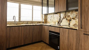 A bespoke luxury kitchen renovation by InStyle Direct featuring dark wood cabinetry, a striking gold and black marble splashback, and premium integrated appliances in Chelsea.