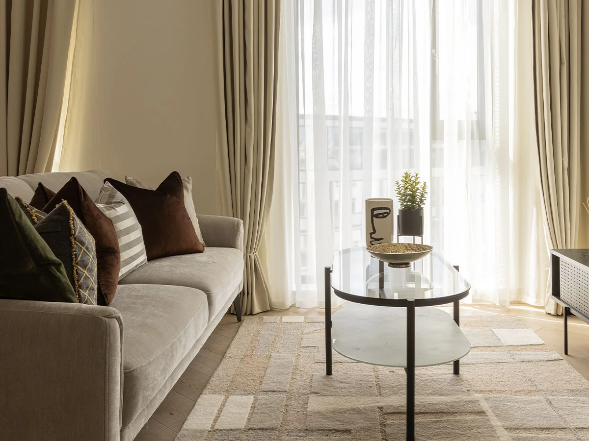 Bright living room with beige sofa, glass coffee table, and natural light of Pembridge Gardens, Notting Hill