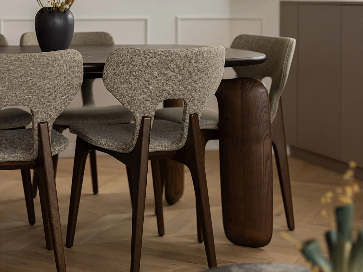 A contemporary dining area styled by InStyle Direct featuring a dark wood table with unique curved legs and designer upholstered chairs with a textured grey fabric in Finchley.