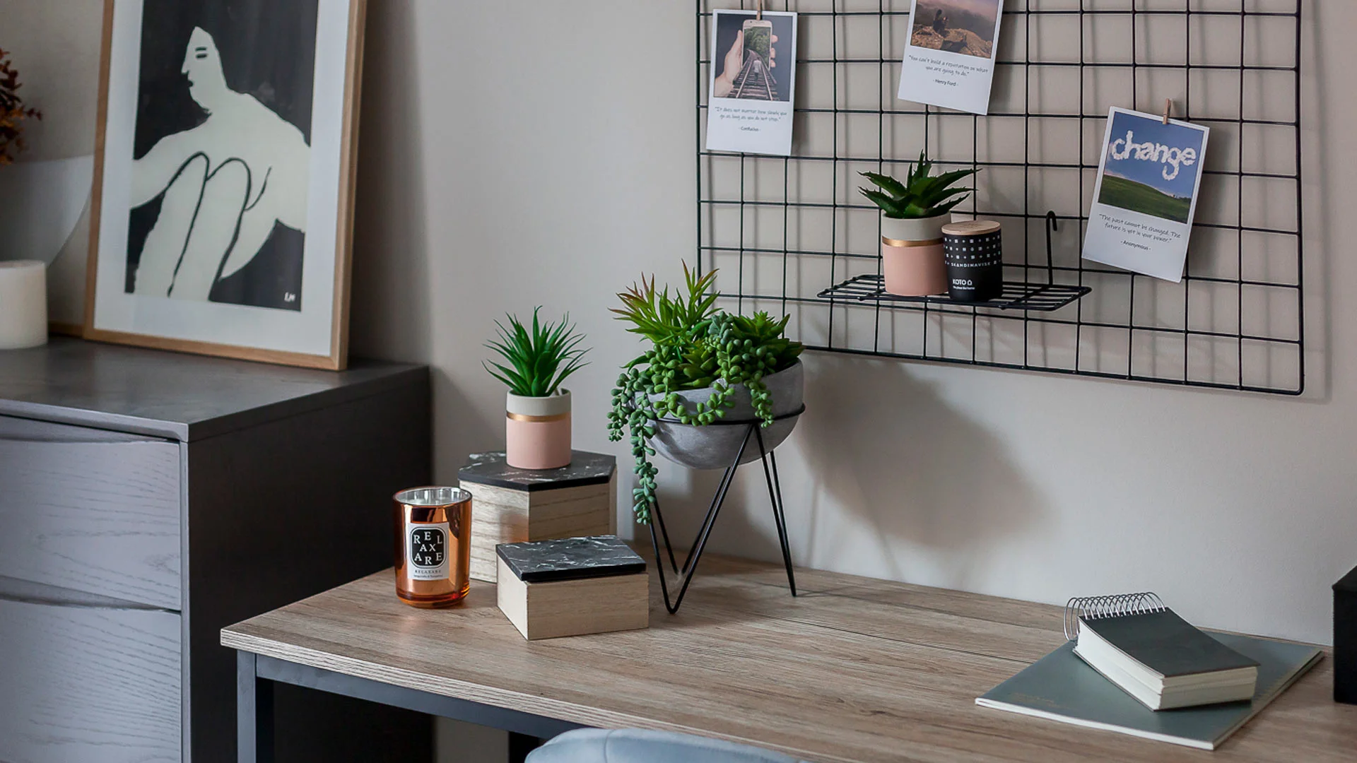 A contemporary workspace styled by InStyle Direct featuring a copper-scented candle, marble-topped storage boxes, and monochrome abstract wall art above a light wood desk in London.
