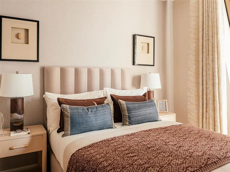 A modern bedroom featuring stylish Furniture Packages, including a cozy bed with layered pillows, a white bedside table, and contemporary wall art