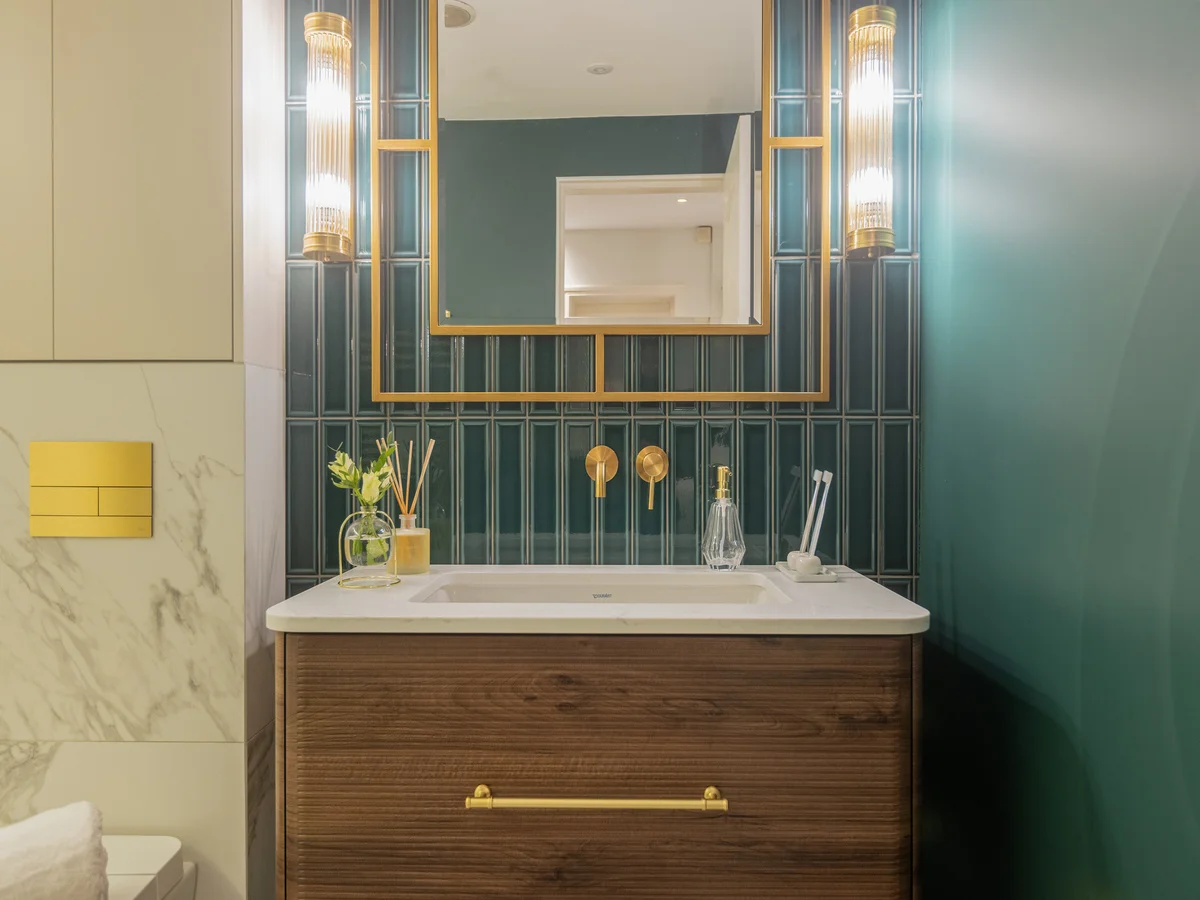 Designer bathroom vanity with mirror lighting and brass details in a modern interior