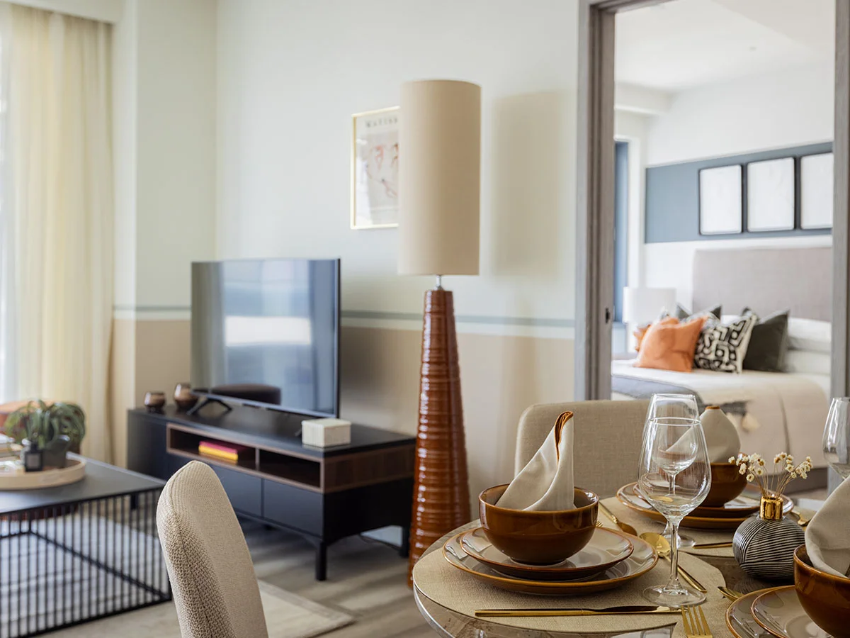 A close-up of a neutral fabric sofa in a Pintail Heights apartment, Hendon, styled by InStyle Direct with velvet gold and dark green patterned cushions and a matching green textured throw