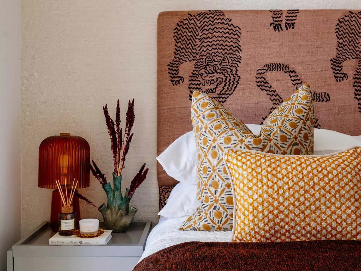 A close-up of an eclectic bedroom at the Aspen project, featuring a statement headboard with a stylized tiger print and bold yellow patterned cushions