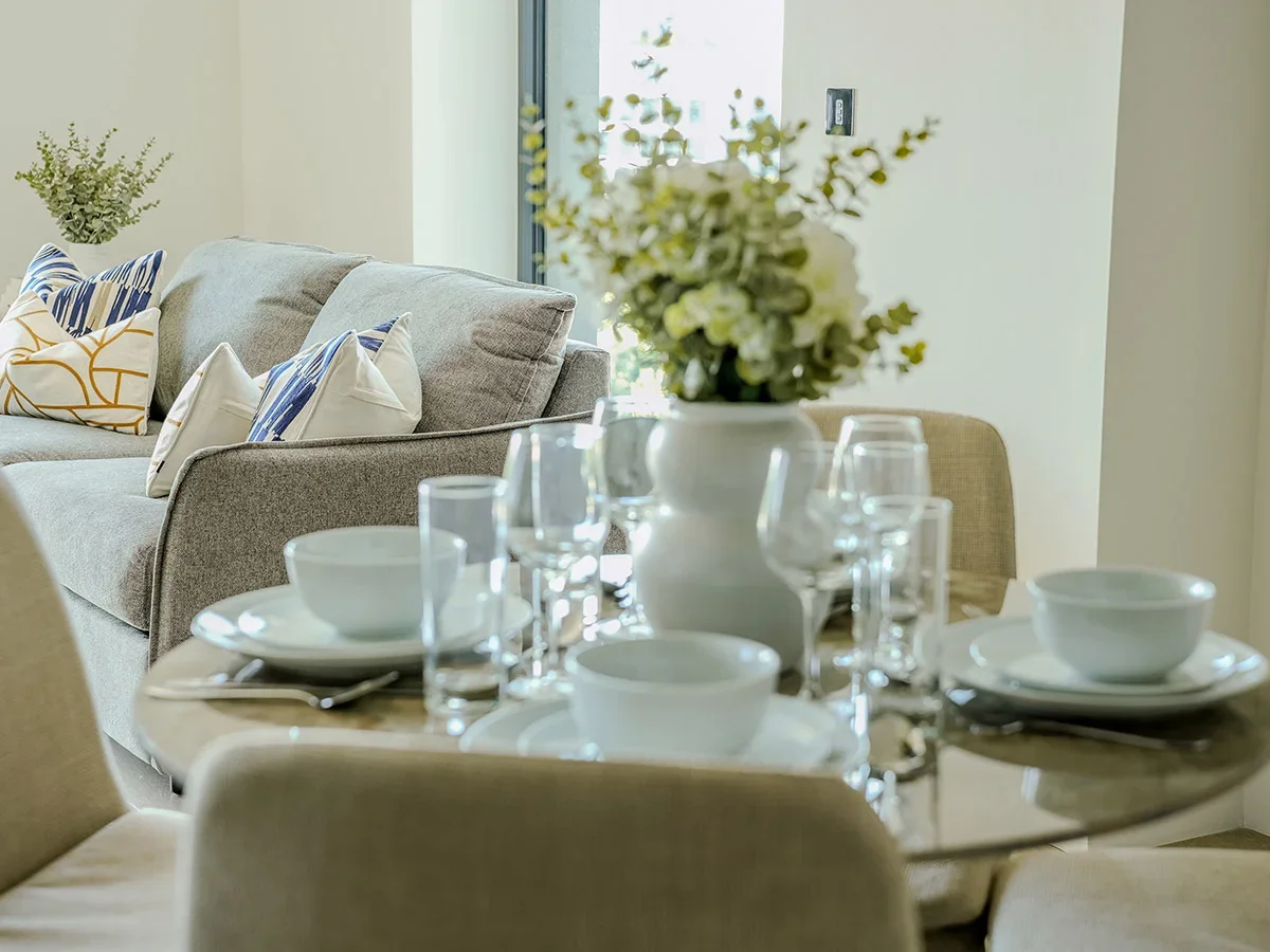 A modern bedroom featuring stylish Furniture Packages, including a cozy bed with layered pillows, a white bedside table, and contemporary wall art