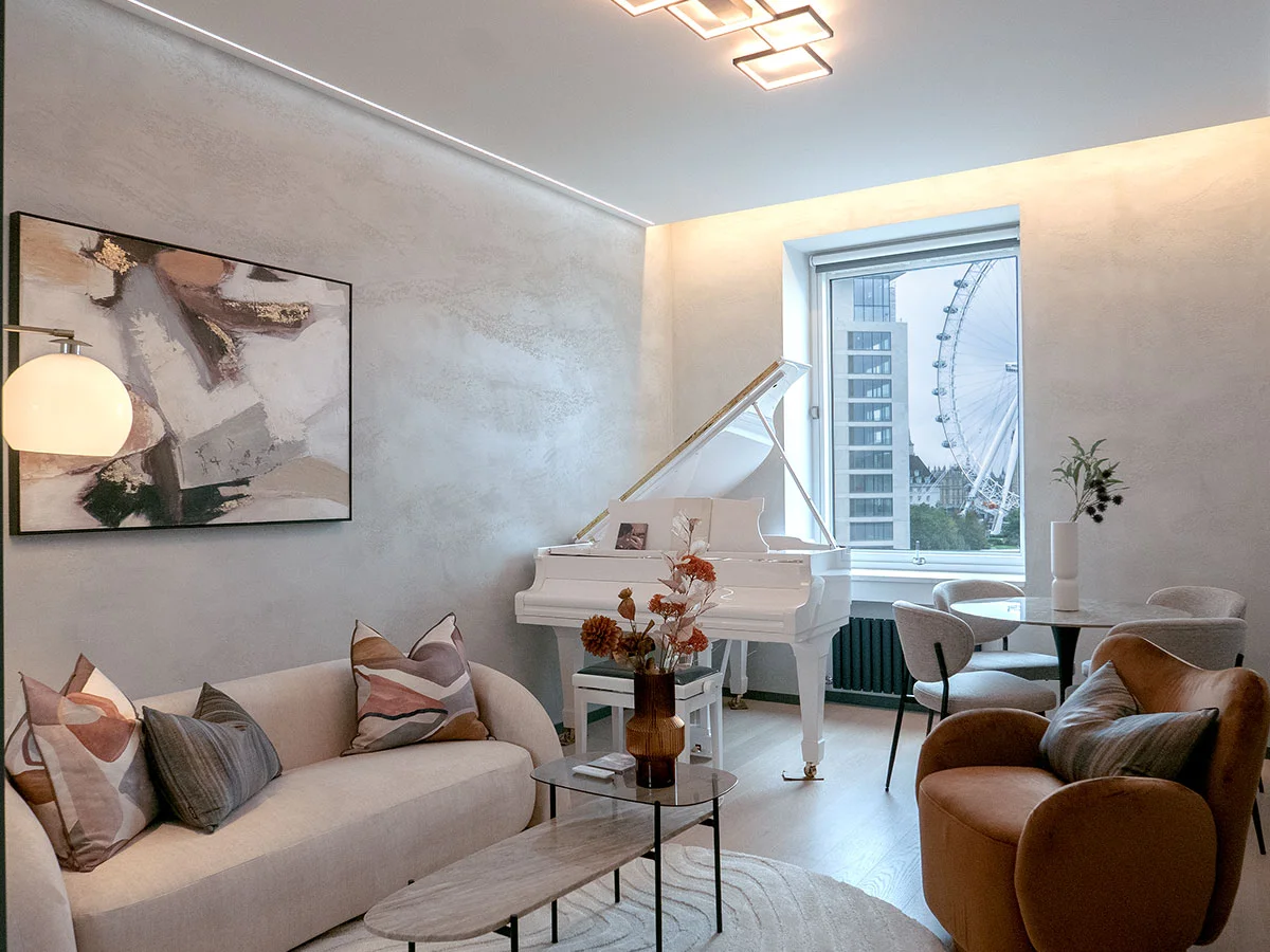 A luxury London apartment living room featuring a white baby grand piano, a terracotta armchair, and a view of the London Eye