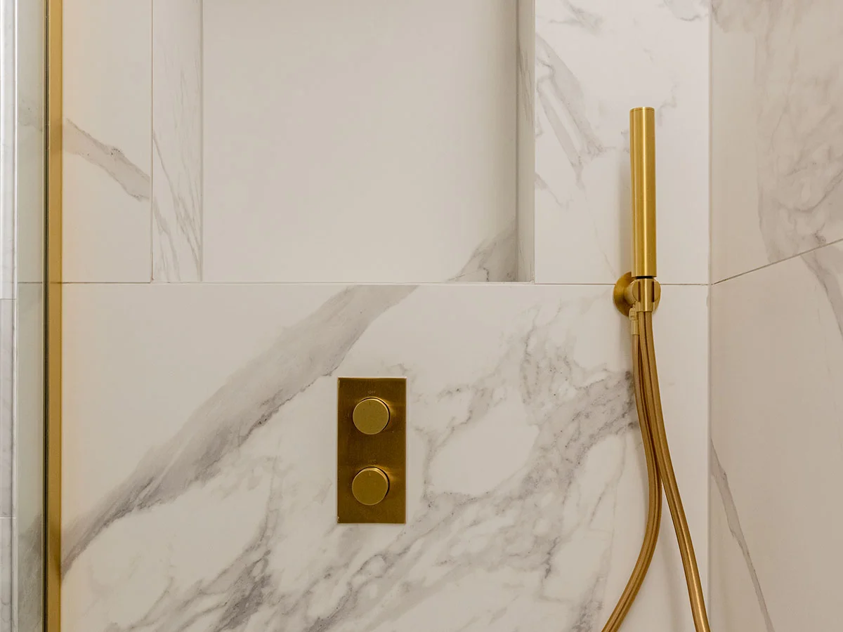 Luxury bathroom shower detail with brass fittings and marble wall finish in Hyde Park apartment