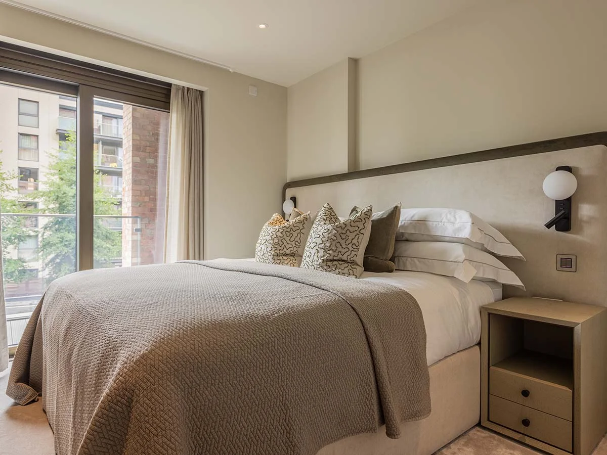 Elegantly dressed bed with neutral tones and designer lighting in a London show home