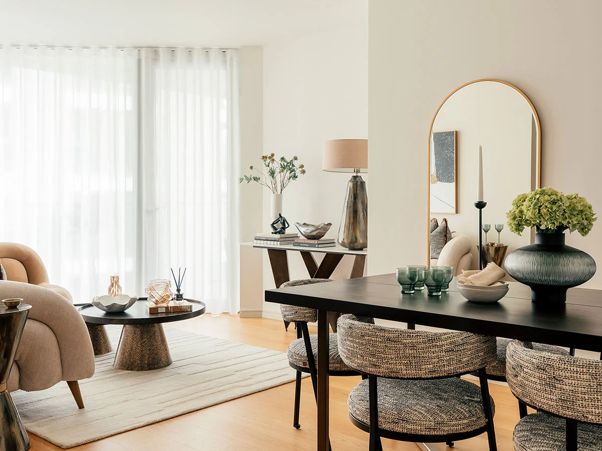 A luxury bedroom styled by InStyle Direct featuring a large round gold-framed mirror, a cream-colored headboard, and a stylish round boucle cushion on the bed with abstract wall art in the background in Chelsea