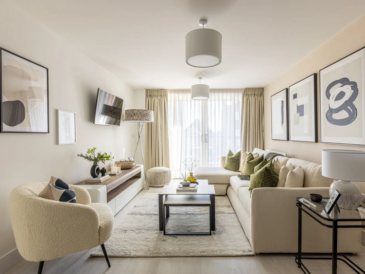 A luxury open-plan living room styled by InStyle Direct featuring a large cream L-shaped sofa with green velvet cushions, a textured boucle armchair, a wooden media unit, and floor-to-ceiling sheer curtains in Watford.