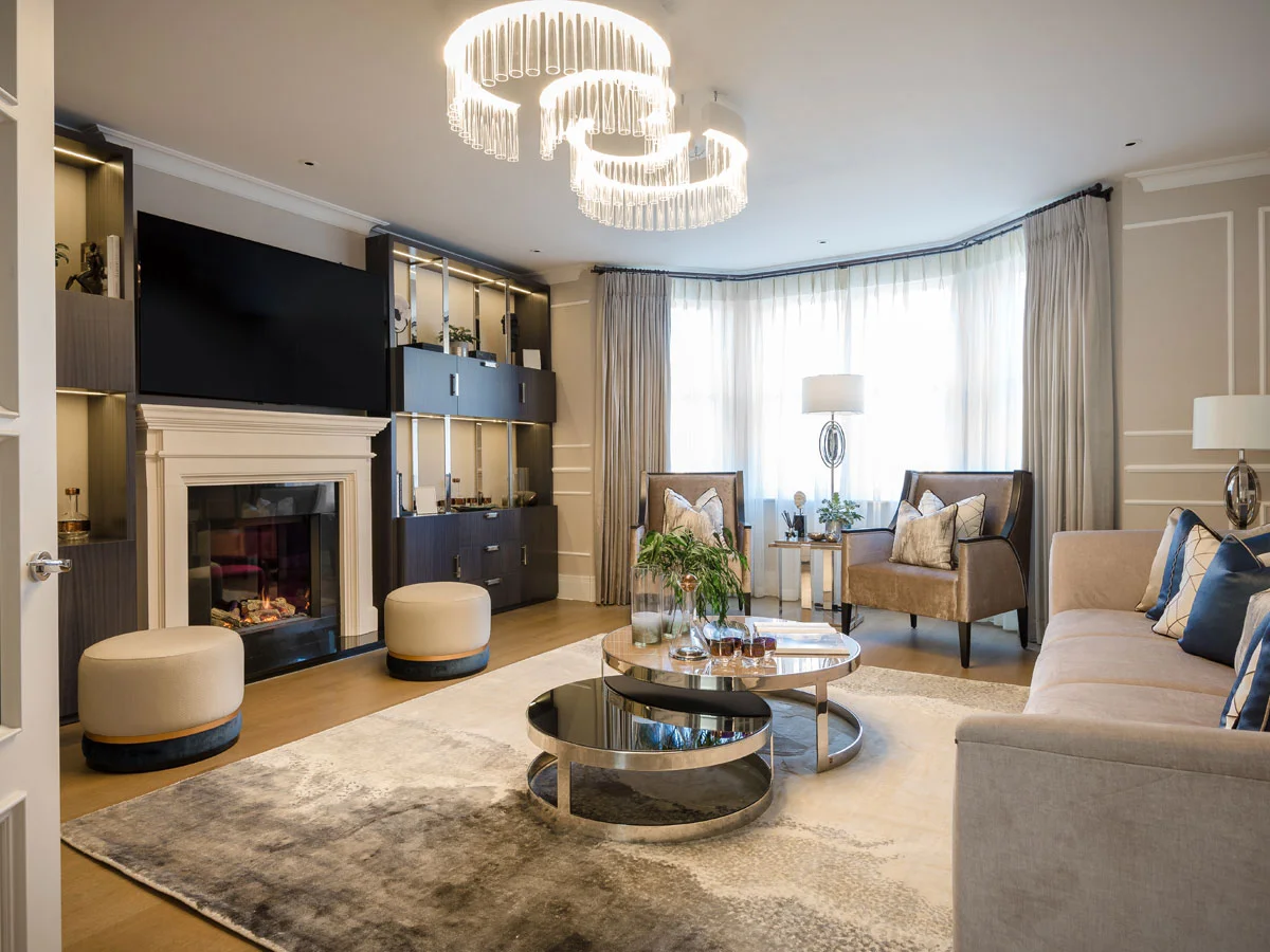 A luxury living room styled by InStyle Direct featuring a bespoke dark wood media wall with integrated lighting, a white marble fireplace, tiered circular coffee tables, and elegant neutral seating in Richmond.