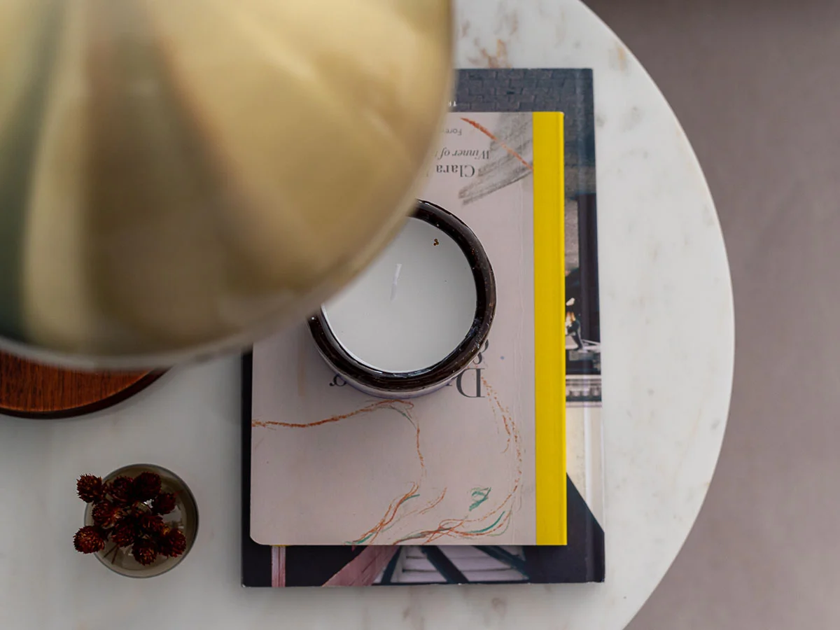 Close-up of professionally staged marble side table with books and candle. Detail in a London show home.