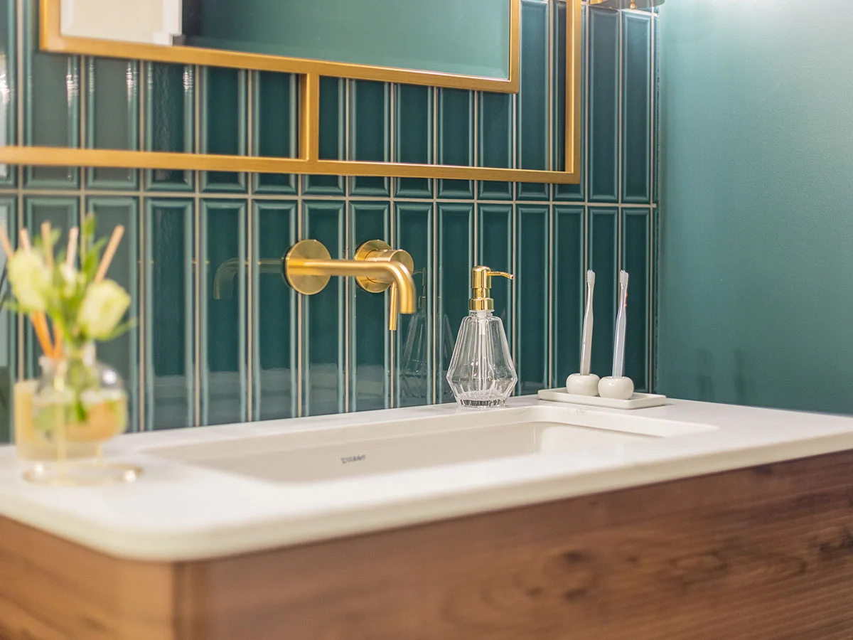 Contemporary bathroom with green tiled wall and brass fittings creating a bold modern look