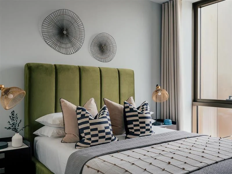 Modern bedroom with olive green headboard and geometric pillows