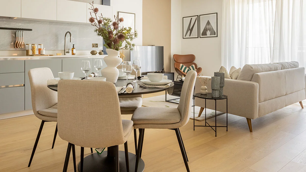 A modern dining area furniture set by InStyle Direct featuring mustard yellow upholstered chairs around a wooden table, an elegant autumnal floral arrangement, and a view into a bright London apartment