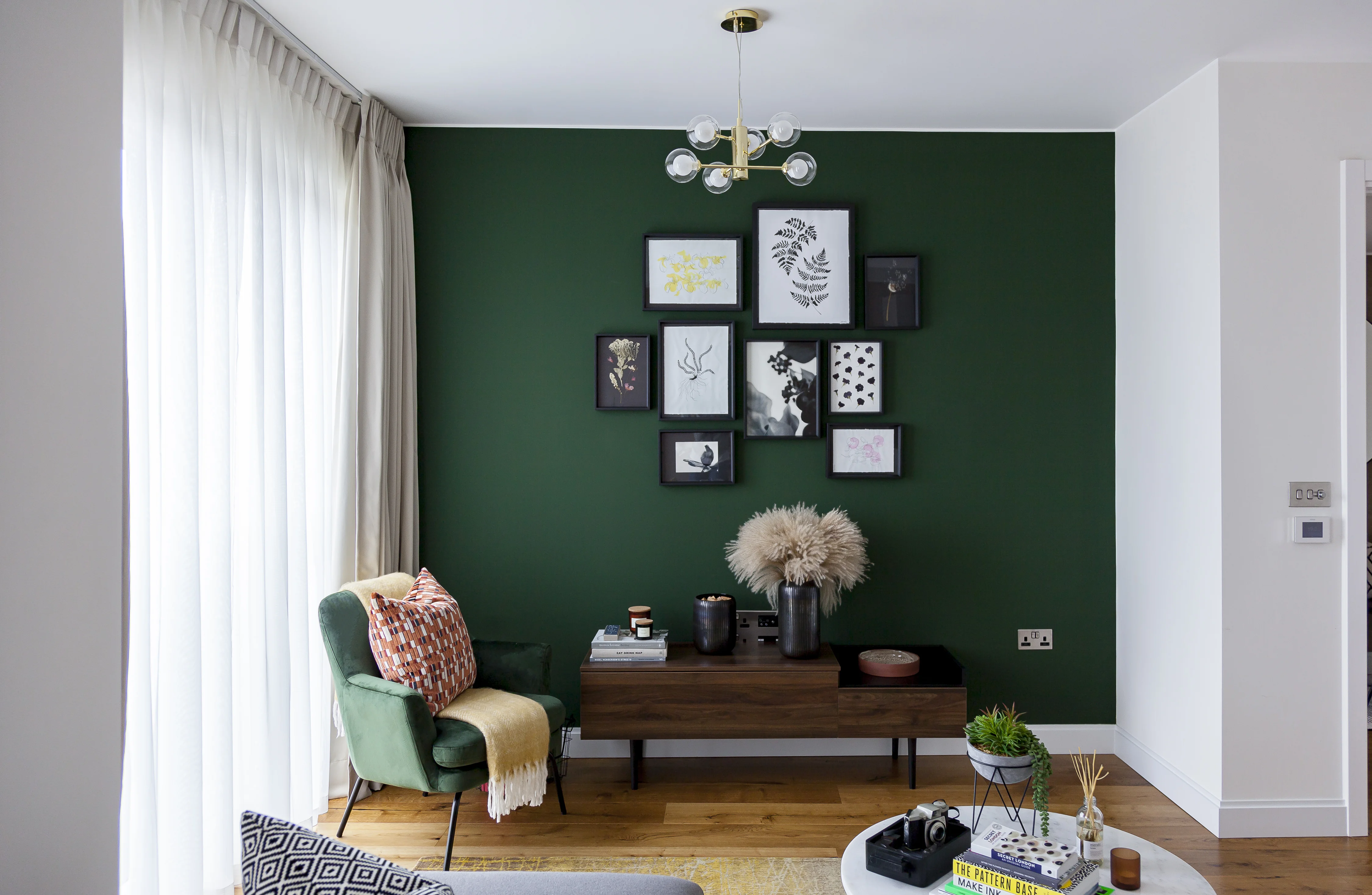 A contemporary open-plan living room styled by InStyle Direct featuring a curved beige sofa, a large abstract wall art piece, and a modern tan lounge chair in Chelsea