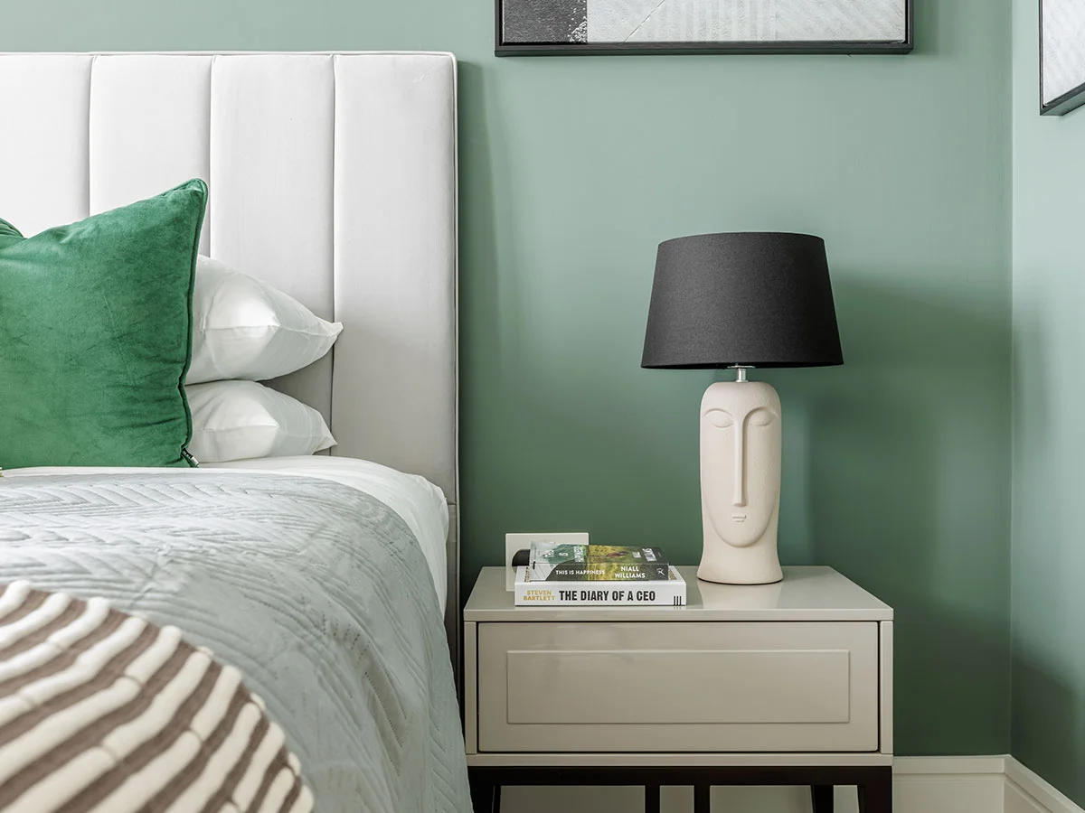 A modern bedroom featuring stylish Furniture Packages, including a cozy bed with layered pillows, a white bedside table, and contemporary wall art