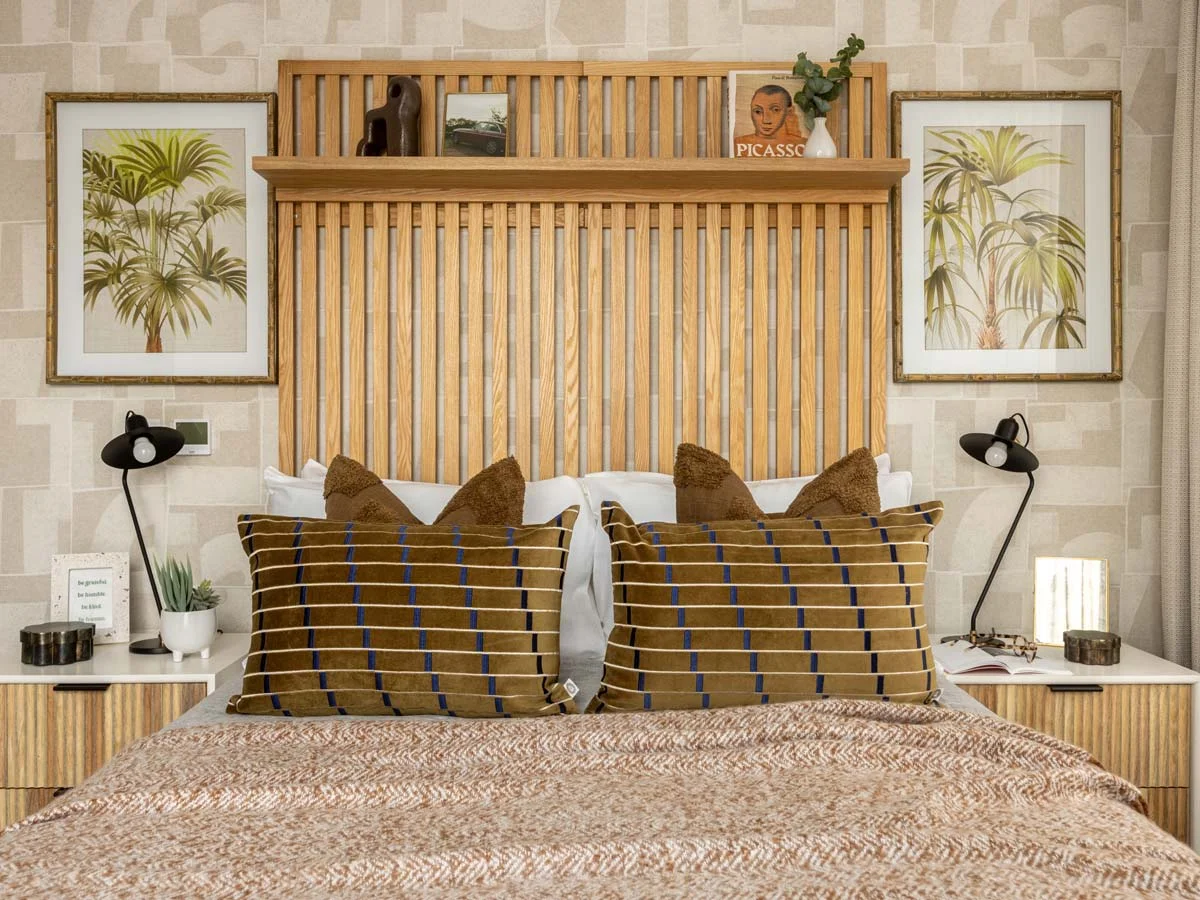 Modern open-plan apartment featuring a stylish dining setup and contemporary living area, showcasing Long-Let Furniture Packages in Dubai designed for comfort and eleganceA stylish show home bedroom featuring a large slatted oak headboard with a display shelf, geometric wallpaper, and framed palm tree art