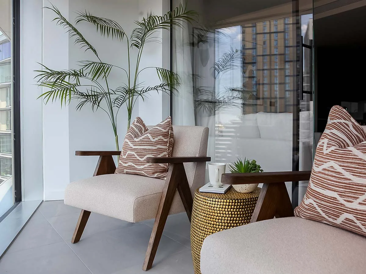 A stylishly furnished winter garden, designed for property investors to maximize rental appeal with modern armchairs and a brass side table