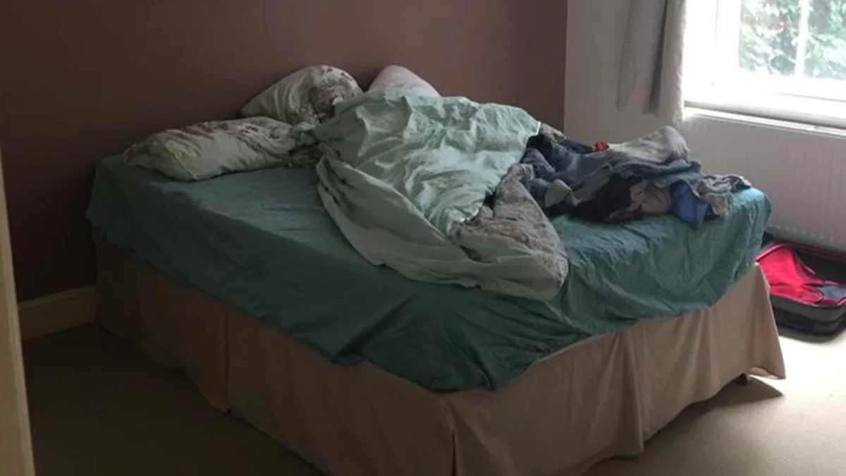 A poorly lit bedroom with an unmade bed and cluttered luggage before receiving a professional property styling makeover by InStyle Direct.