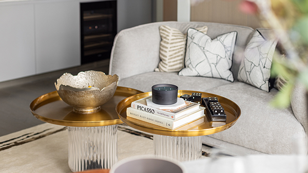 Modern living room with gold accent tables, decorative bowl, books, and cushions on a neutral sofa, showcasing turnkey interiors Dubai style