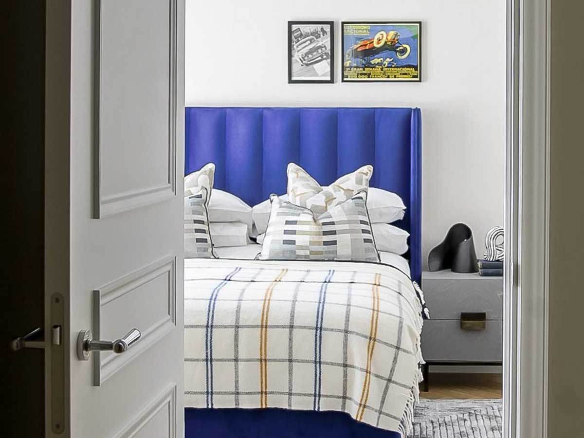 A stylish bedroom with a bold blue headboard, layered cushions, and a soft patterned throw, showcasing the refined aesthetic of residential interior design Dubai