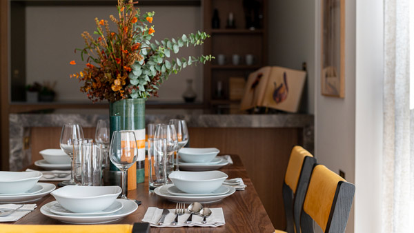 A beautifully set dining table with elegant dinnerware and warm-toned décor, capturing the polished atmosphere often seen in high-end show homes for developers