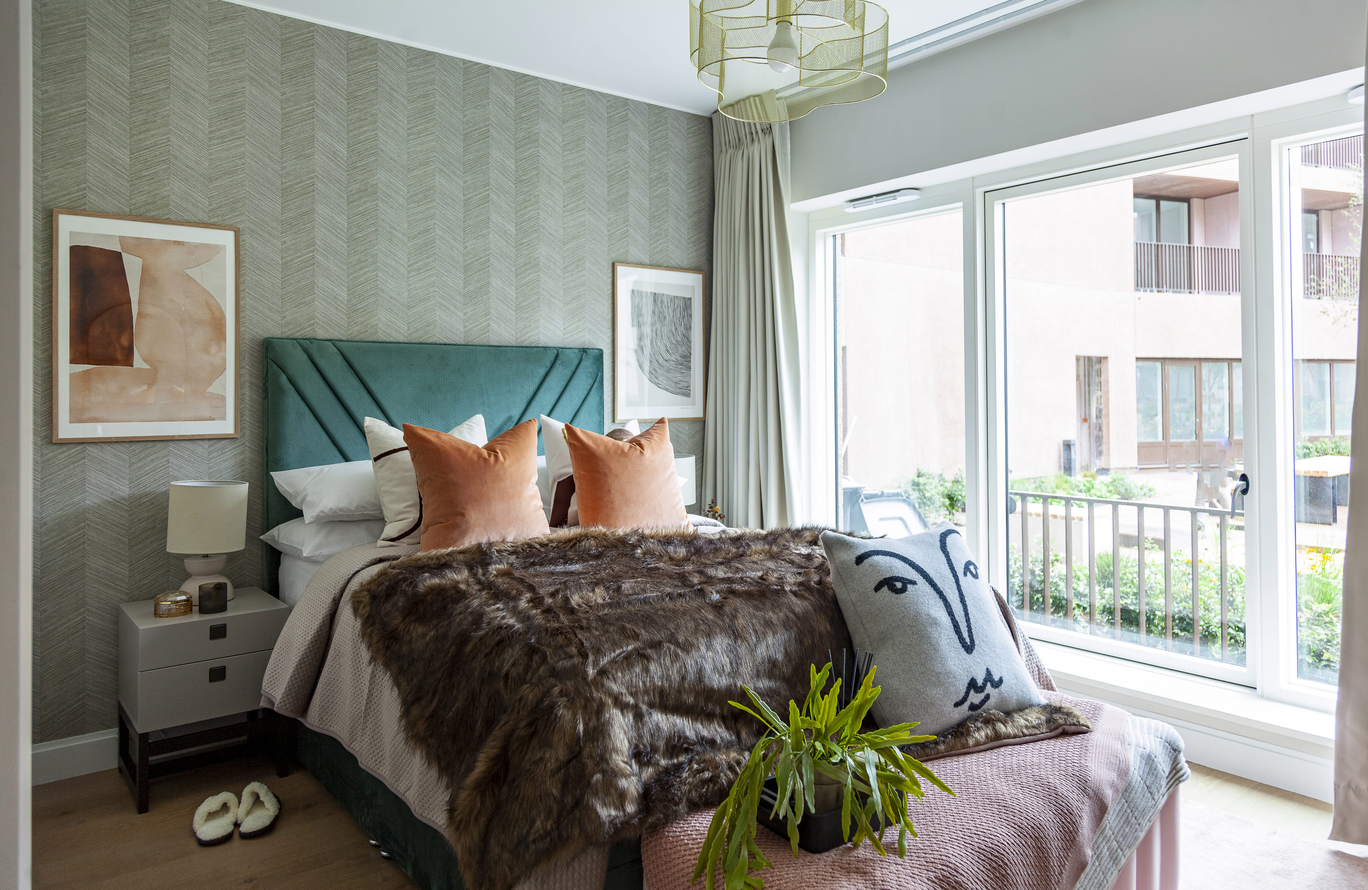 Professionally furnished London flat bedroom with emerald green headboard and textured wallpaper.