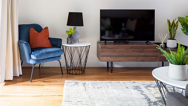 Media corner with blue chair – furnished for tenants TV corner with blue accent chair, wood media unit and plants, furnished for London tenants